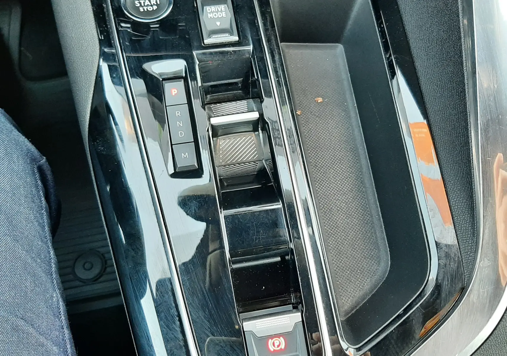 Vue rapprochée de la console centrale noire brillante du Peugeot 3008 2023 avec sélecteur de boîte auto et bouton start/stop.