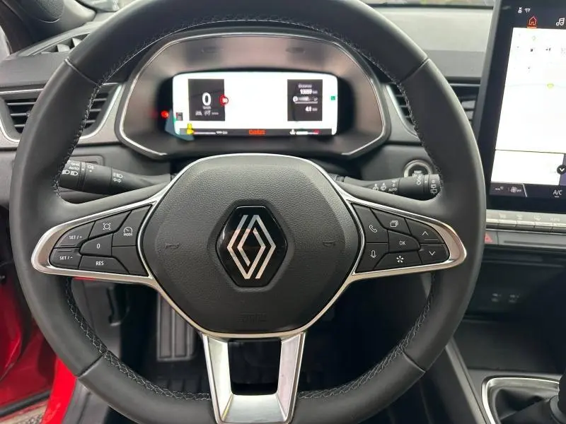 Vue rapprochée du volant noir du Renault Captur 2025 Rouge Flamme/Noir Étoilé avec tableau de bord numérique et écran tactile.