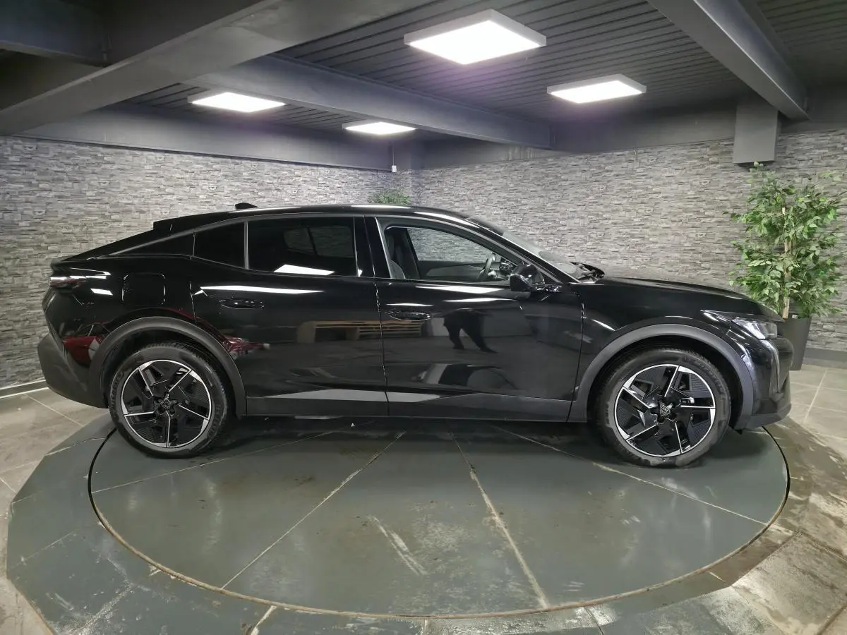 Vue de profil côté gauche d’une Peugeot 408 électrique noire Perla Nera avec jantes alliage 19 pouces diamantées.