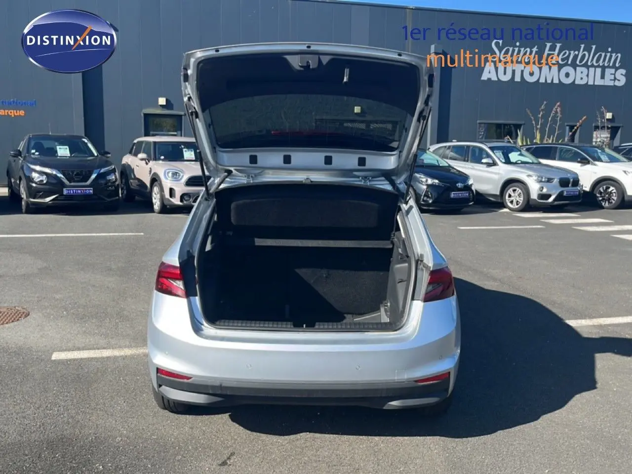 Vue arrière d'une Skoda Fabia 2025 Reflex Silver avec coffre ouvert sur un parking extérieur.