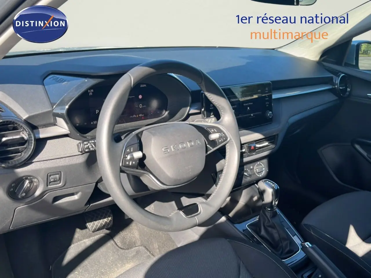 Intérieur de la Skoda Fabia 2025 en vue côté conducteur, tableau de bord gris noir avec volant multifonction et boîte auto.