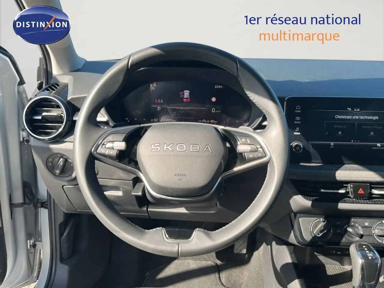 Vue intérieure centrée sur le volant SKODA d'une Fabia 2025, avec tableau de bord numérique et écran tactile.