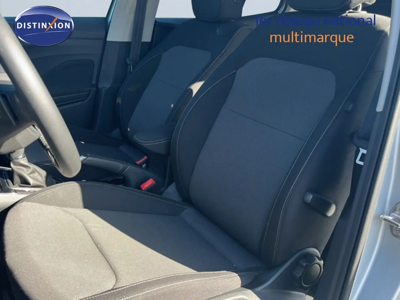 Vue intérieure côté conducteur de la Skoda Fabia 2025 en tissu gris noir, avec volant multifonction et porte ouverte.