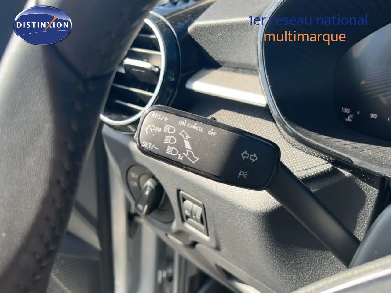 Gros plan sur la commande de régulateur de vitesse à gauche du volant dans l’habitacle gris noir de la Skoda Fabia 2025.