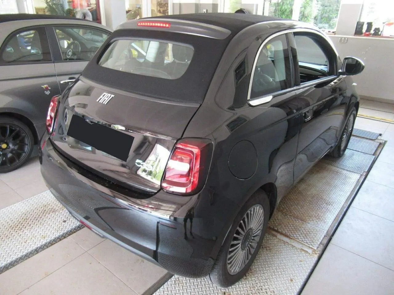 Vue 3/4 arrière droite d'une FIAT 500 Cabriolet électrique noire avec capote noire et jantes alliage 16 pouces.