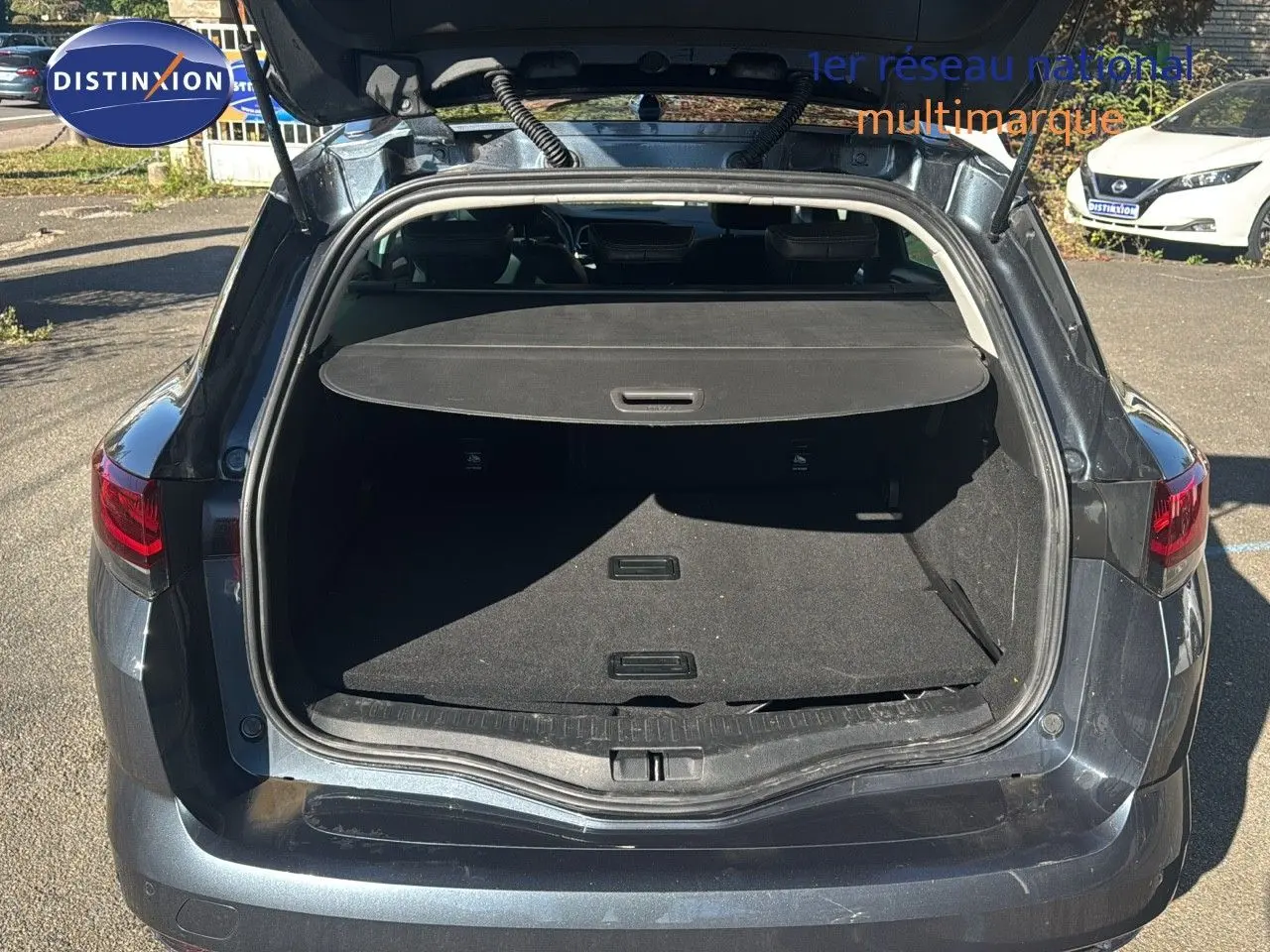 Coffre ouvert vu de l'arrière d'une Renault Mégane Break gris titanium métal, montrant l'espace de chargement.