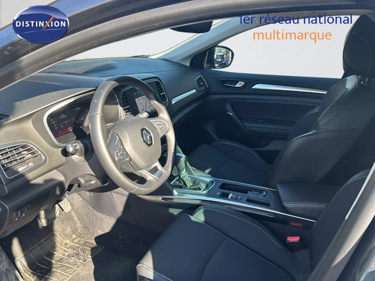 Intérieur de Renault Mégane Break 2024 en vue côté conducteur, sièges noirs et tableau de bord moderne.