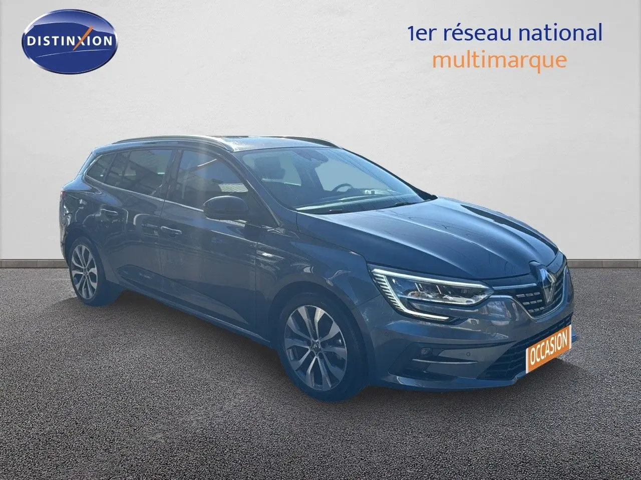 Renault Mégane Break gris titanium métal vue 3/4 avant droit avec phares LED allumés sur fond neutre.