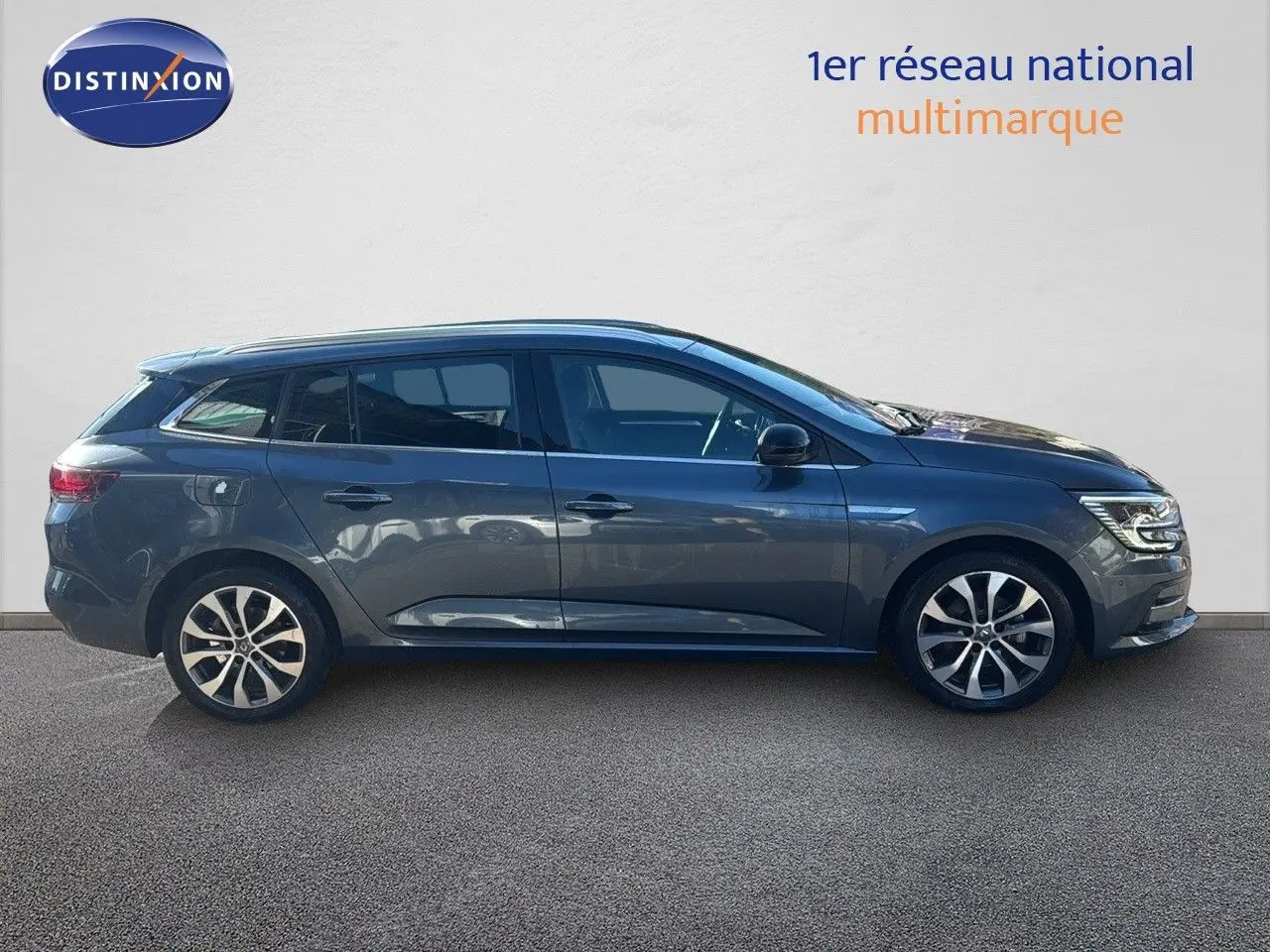 Profil droit d'une Renault Mégane Break gris titanium métal 2024 avec jantes alliage bicolores et vitres teintées.