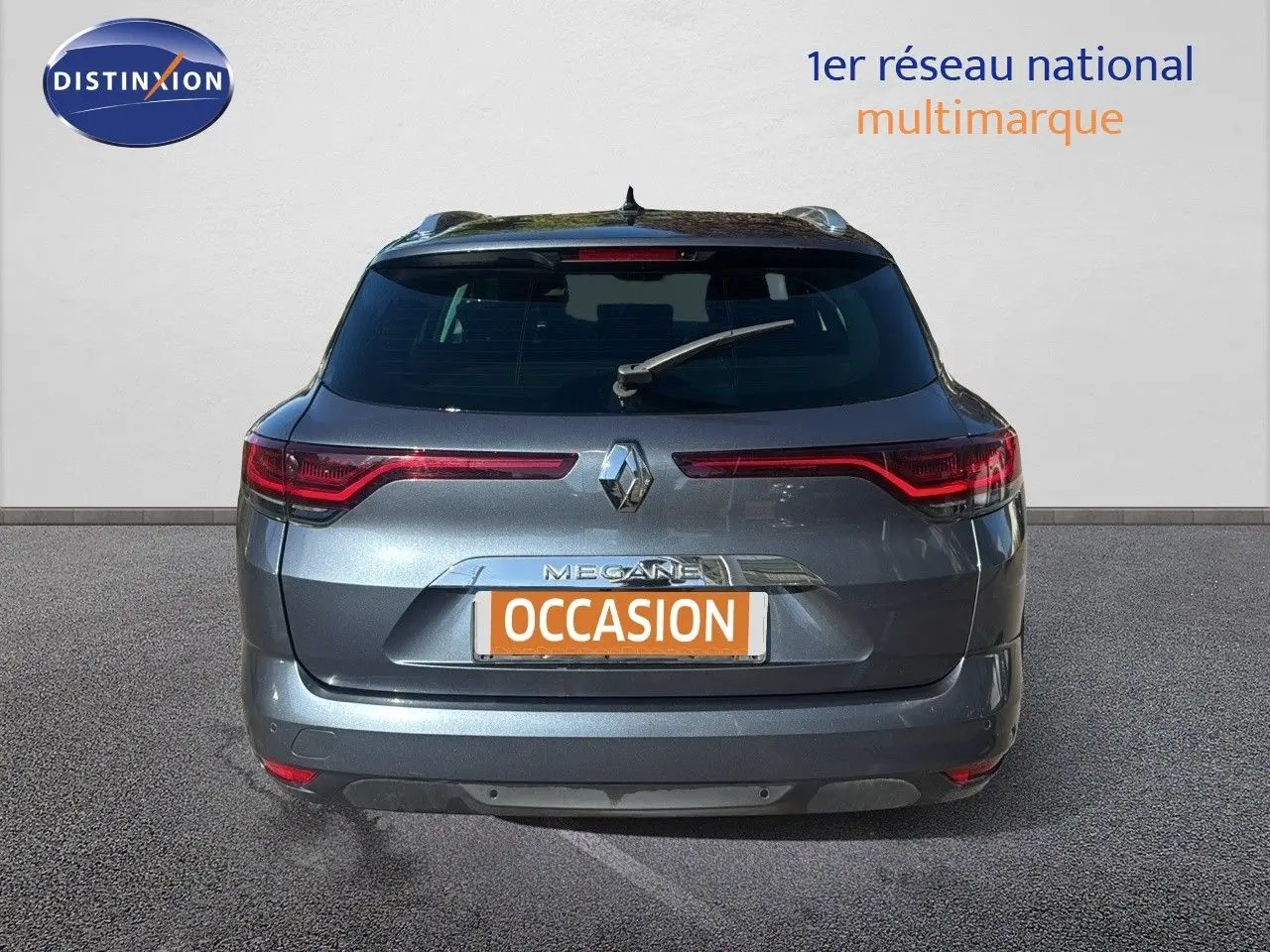 Vue arrière d'une Renault Mégane Break gris titanium métal avec feux LED et logo distinctif au centre.