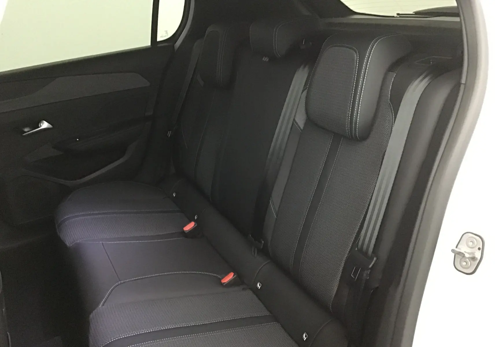 Vue intérieure du siège arrière droit en tissu noir avec surpiqûres blanches d'une Peugeot 308 gris Sellenium 2025.