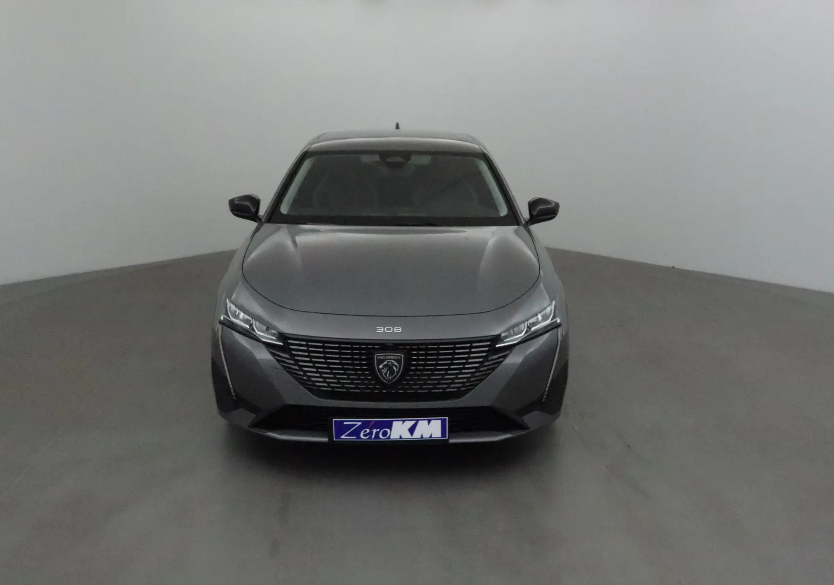 Peugeot 308 gris Sellenium vue de face dans un intérieur neutre avec calandre et logo bien visibles.