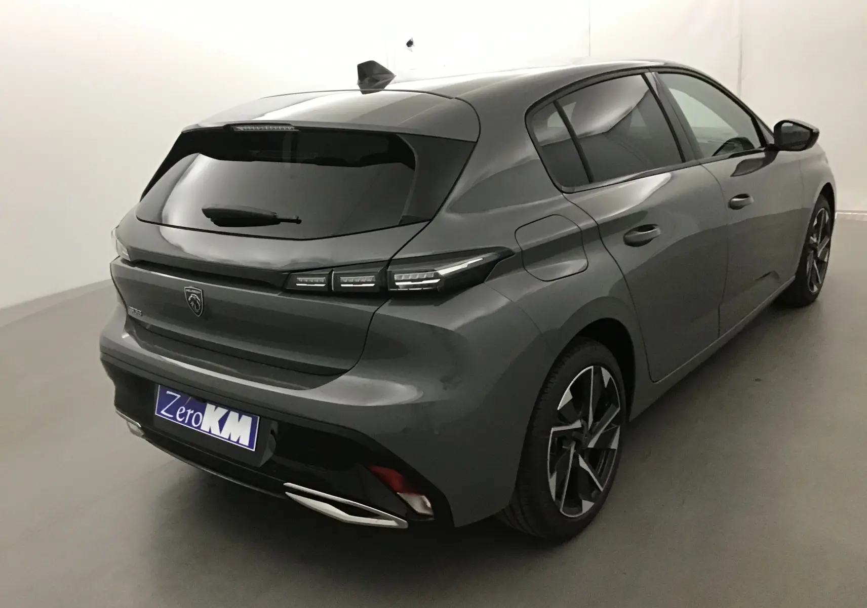 Vue 3/4 arrière droite d'une Peugeot 308 gris Sellenium 2025 avec feux arrière LED et jantes alliage distinctives.