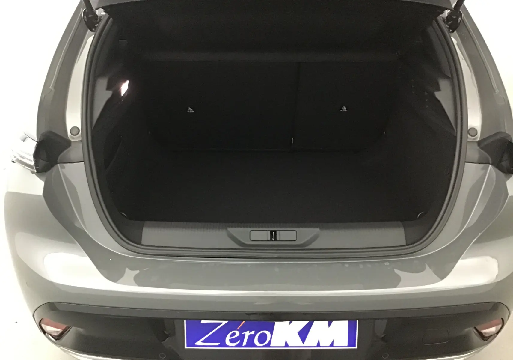 Coffre ouvert vu de l'arrière d'une Peugeot 308 gris Sellenium 2025, soulignant l'espace de chargement vide.