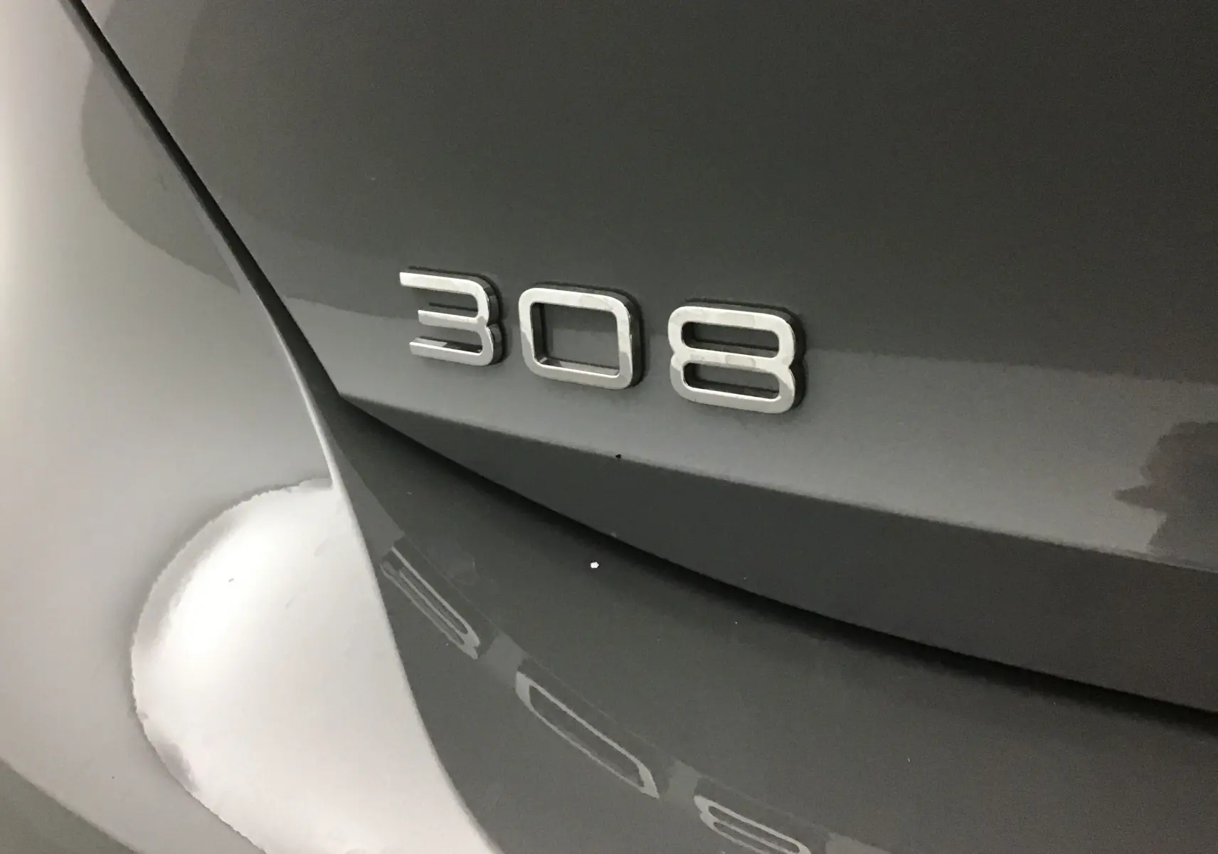 Gros plan sur l'arrière gris Sellenium d'une Peugeot 308 2025 avec le badge du modèle bien visible.