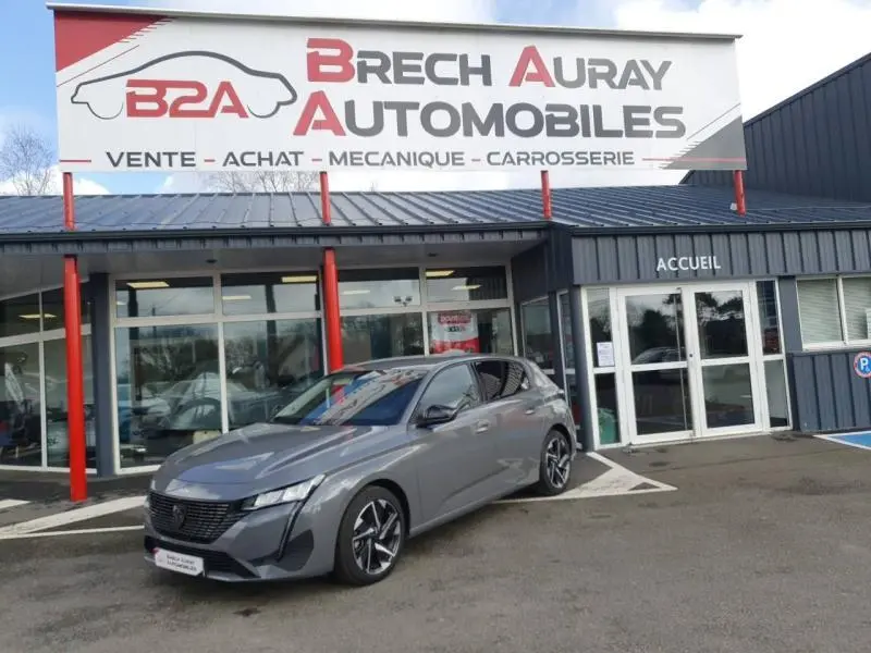 Peugeot 308 gris Sélénium vue 3/4 avant droite devant un garage Brech Auray Automobiles.