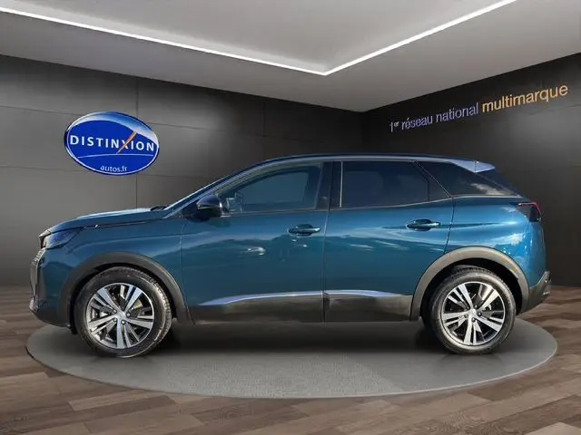 Profil côté gauche d'un Peugeot 3008 2023 bleu Célèbes dans un showroom avec jantes alliage et vitres teintées.
