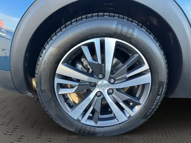 Gros plan sur la roue avant droite du Peugeot 3008 Bleu Célèbes avec jante alliage 18 pouces au design moderne.