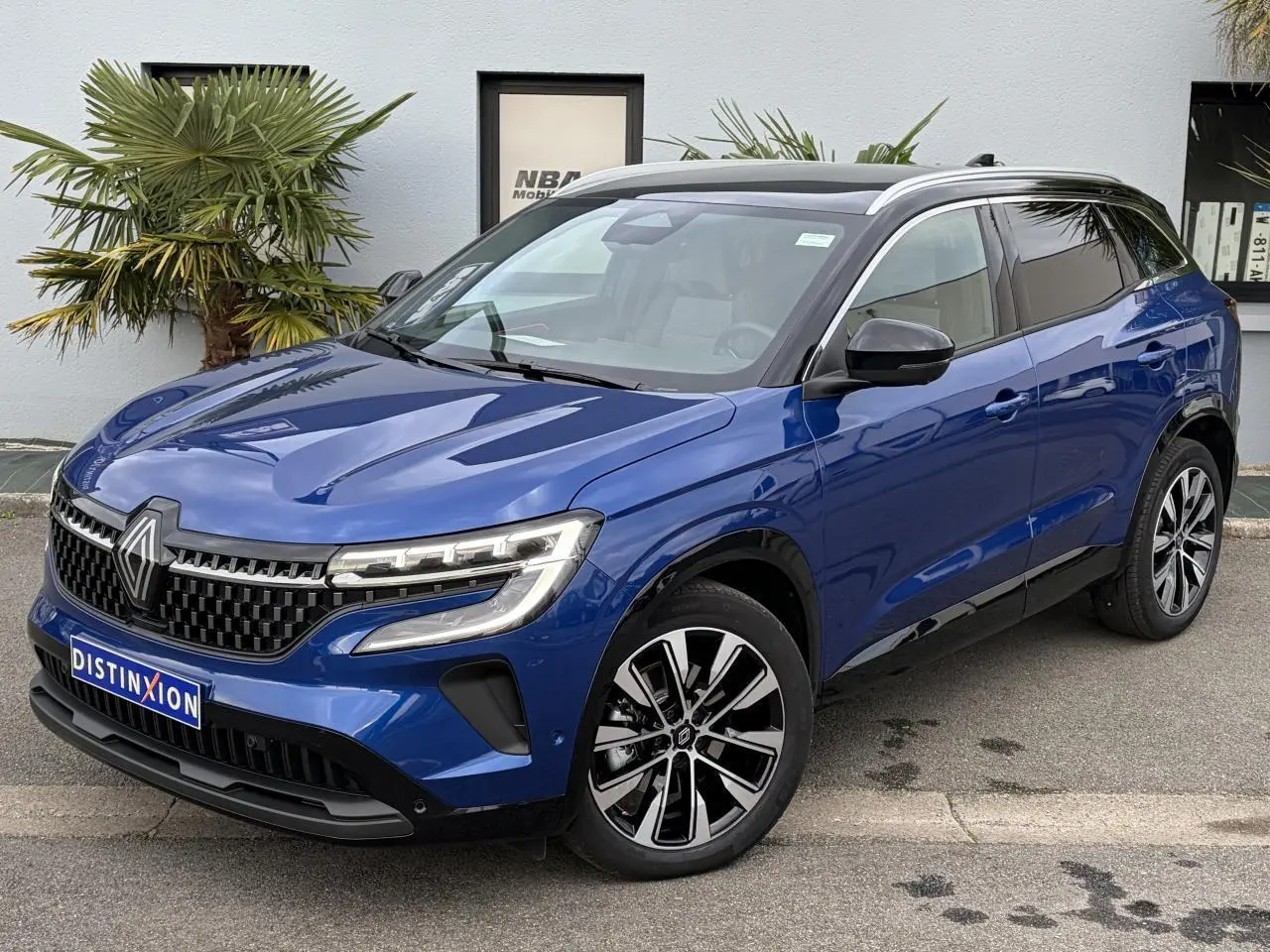 Renault Austral E-Tech hybride bleu Iron vue 3/4 avant droit avec toit panoramique noir et jantes alliage noires.