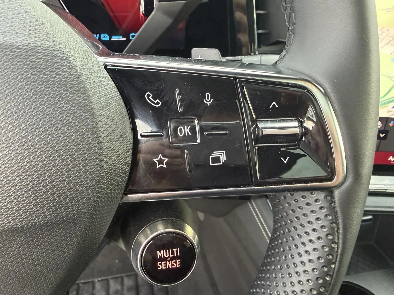 Gros plan sur les commandes au volant en textile grainé noir du Renault Austral E-Tech 2025 avec bouton Multi-Sense.