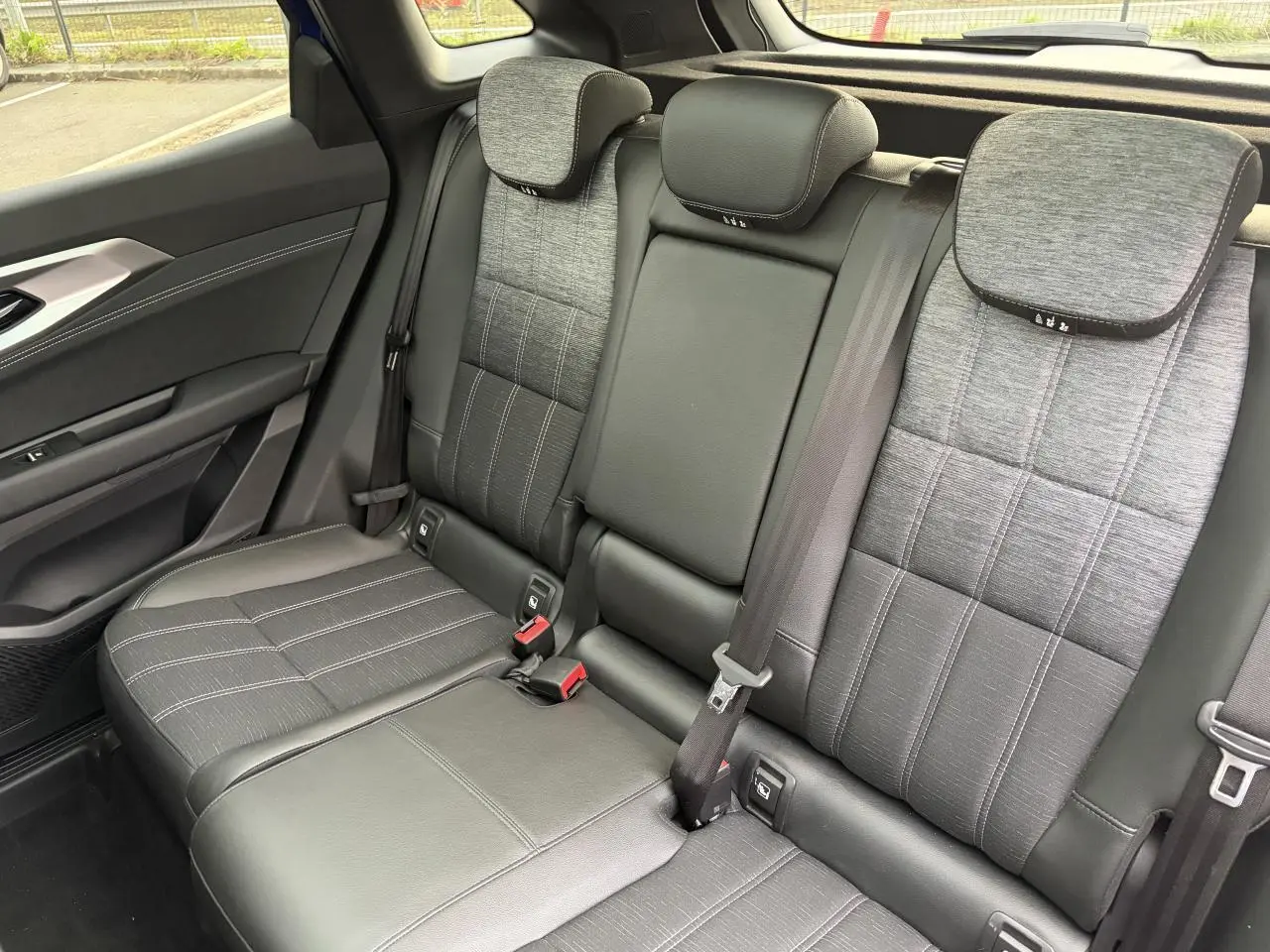 Vue côté droit de la banquette arrière grise mixte tissu et cuir du Renault Austral E-Tech 2025 avec appuie-têtes et ceintures visibles.
