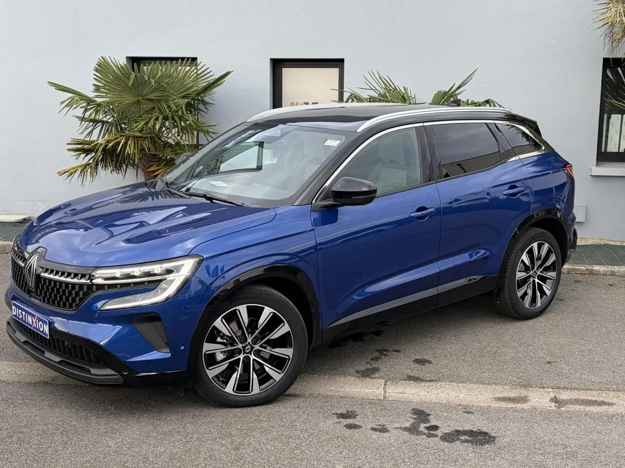 Vue 3/4 avant droit du Renault Austral E-Tech hybride bleu Iron avec toit panoramique noir et jantes alliage 19 pouces.