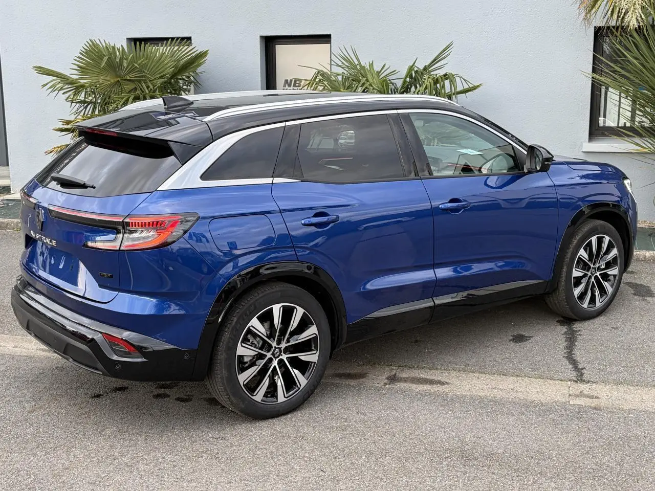 Vue 3/4 arrière droite du Renault Austral E-Tech bleu Iron avec toit noir panoramique et jantes alliage 19 pouces.