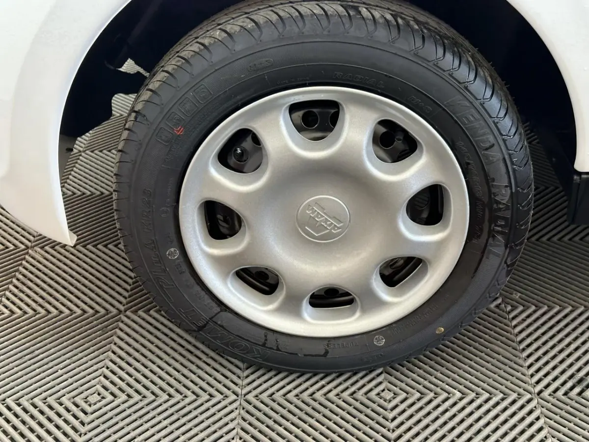 Gros plan sur la roue avant droite d'une Aixam Minauto E Access blanche, montrant le pneu et l'aile du véhicule.