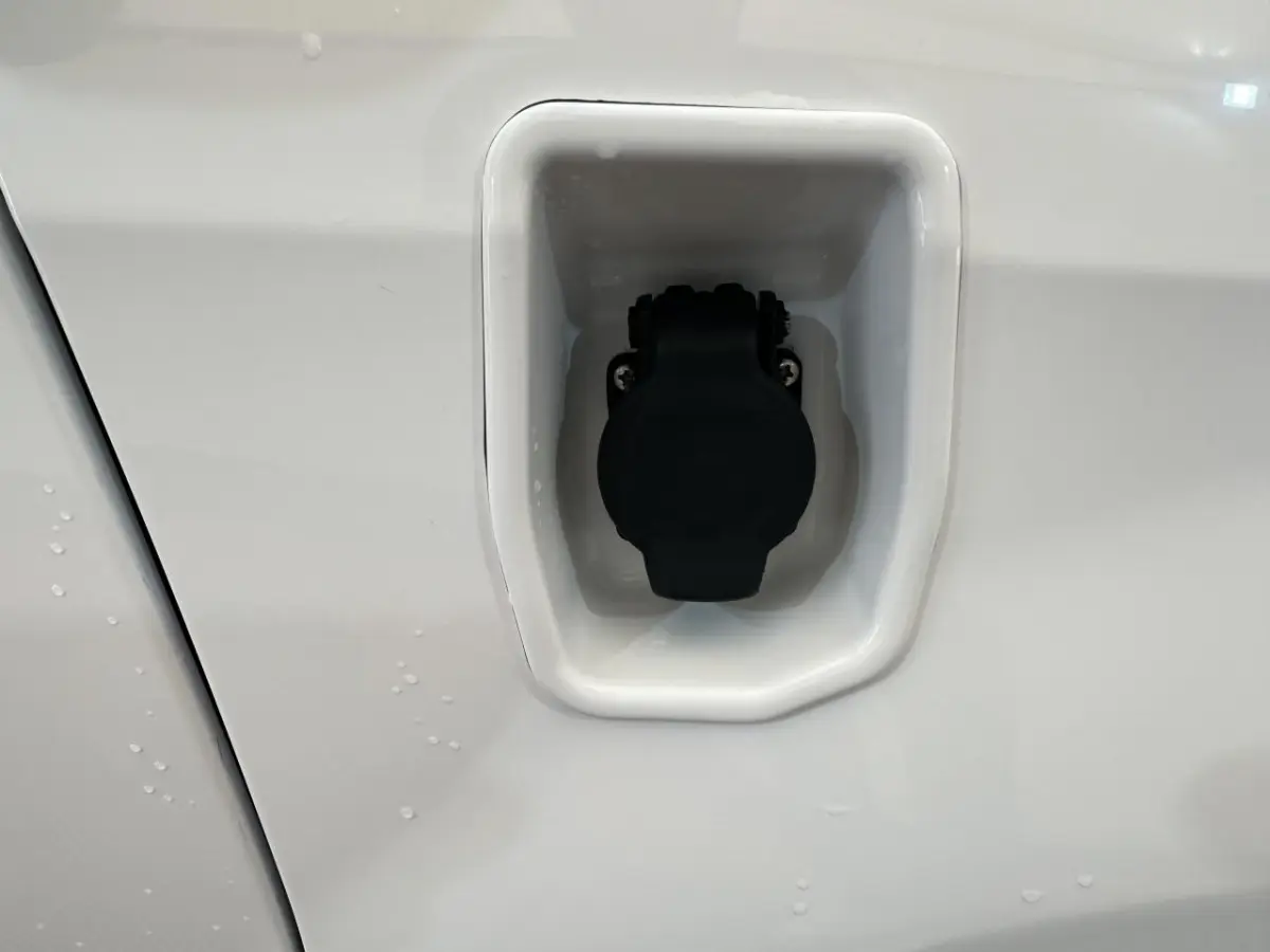 Prise de recharge électrique noire intégrée dans la carrosserie blanche de l'AIXAM MINAUTO E ACCESS 2026.