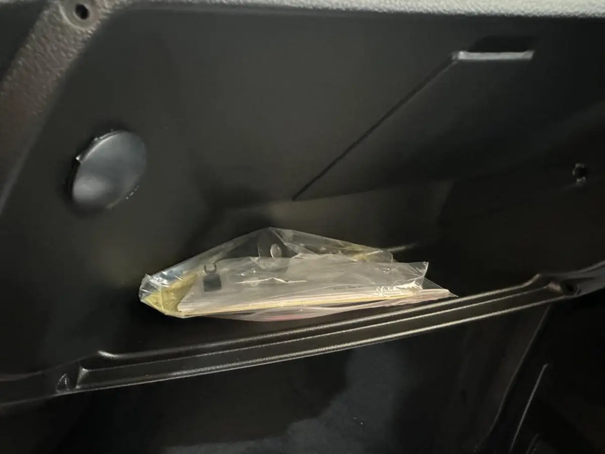 Gros plan sur la boîte à gants noire de l'AIXAM MINAUTO E ACCESS 2026 avec documents plastifiés à l'intérieur.