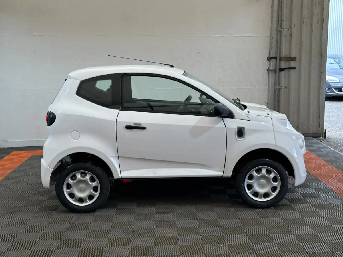Vue de profil côté droit de l'AIXAM MINAUTO E ACCESS 2026 blanche, petite citadine électrique avec rétroviseur caméra conducteur.