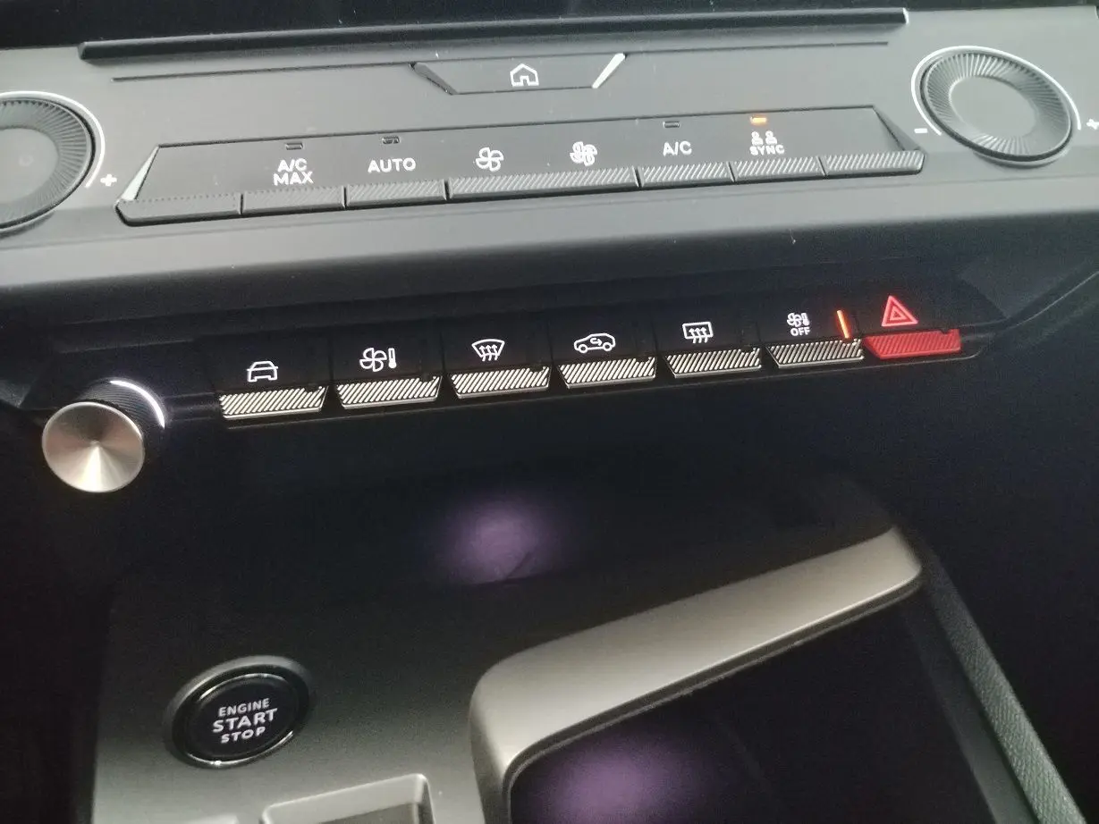 Vue rapprochée du tableau de bord de la Peugeot 308 SW Hybrid 2025, boutons de commande éclairés et bouton start/stop visible.