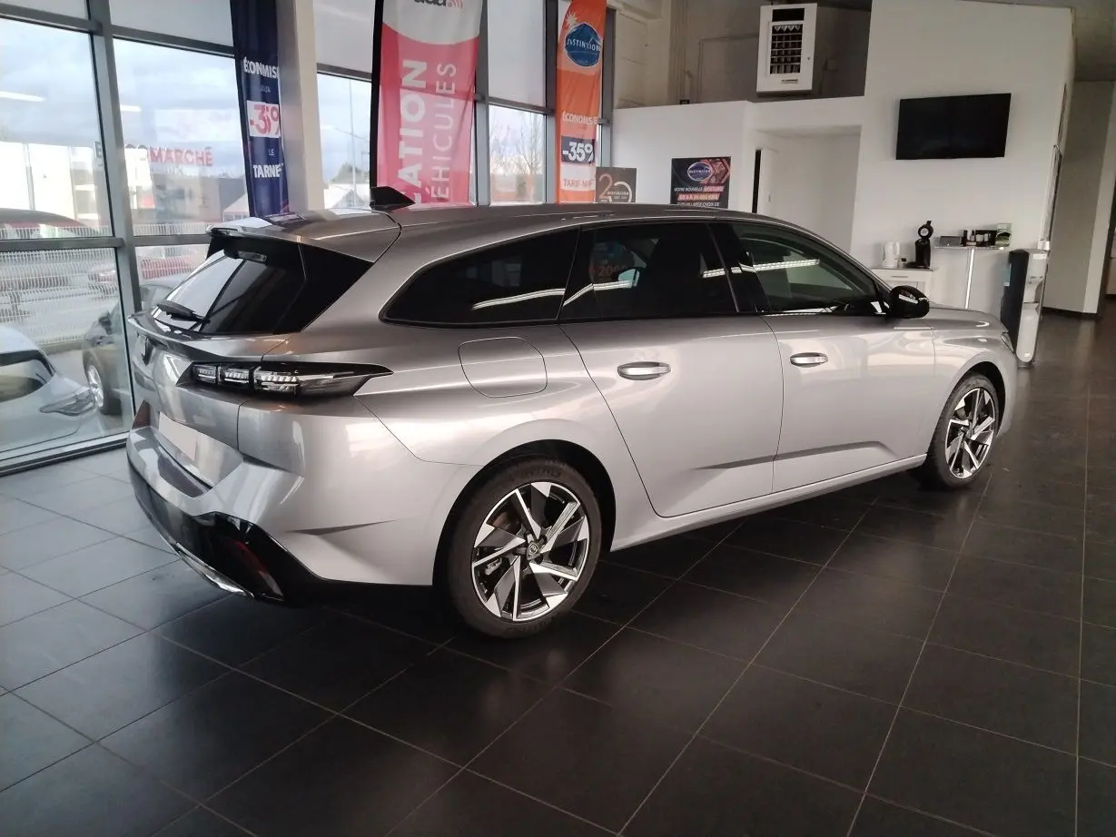 Peugeot 308 SW Hybrid gris Artense vue 3/4 arrière droit en showroom avec jantes alliage et vitres teintées.