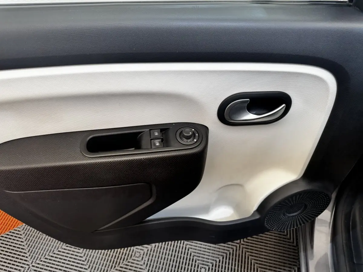 Gros plan sur la porte intérieure côté conducteur de la Renault Twingo gris foncé, avec commandes de vitres et rétroviseurs.