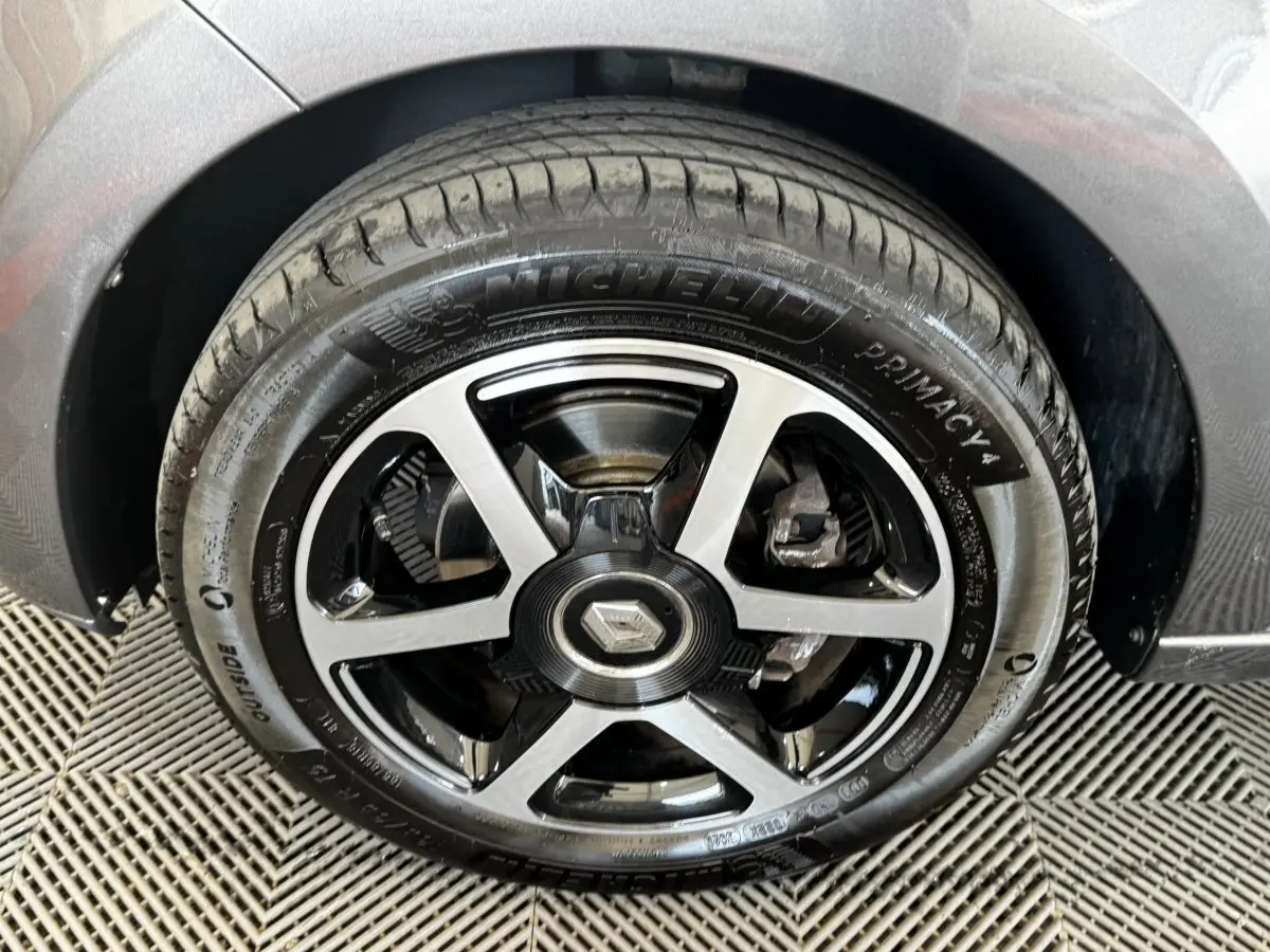 Gros plan sur la roue avant droite d'une Renault Twingo gris foncé, avec jante alliage noire et argentée.