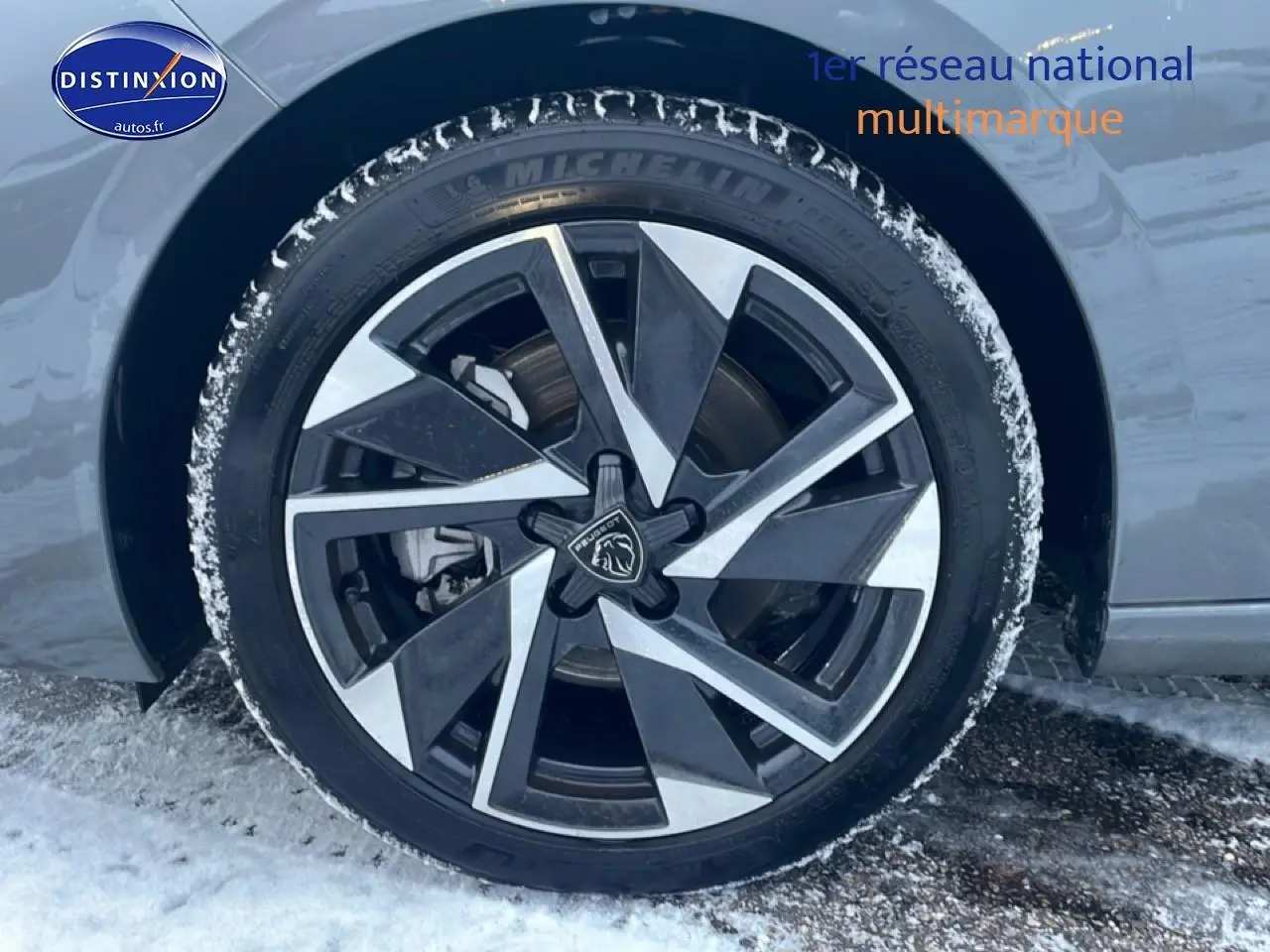 Gros plan sur la jante alu bicolore du côté gauche d'une Peugeot 308 gris sellenium avec traces de neige.