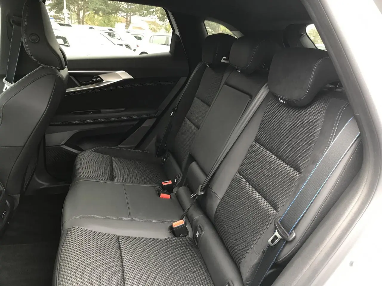 Vue intérieure côté droit des sièges arrière noirs avec surpiqûres bleues du Renault Austral blanc 2025 finition Esprit Alpine.