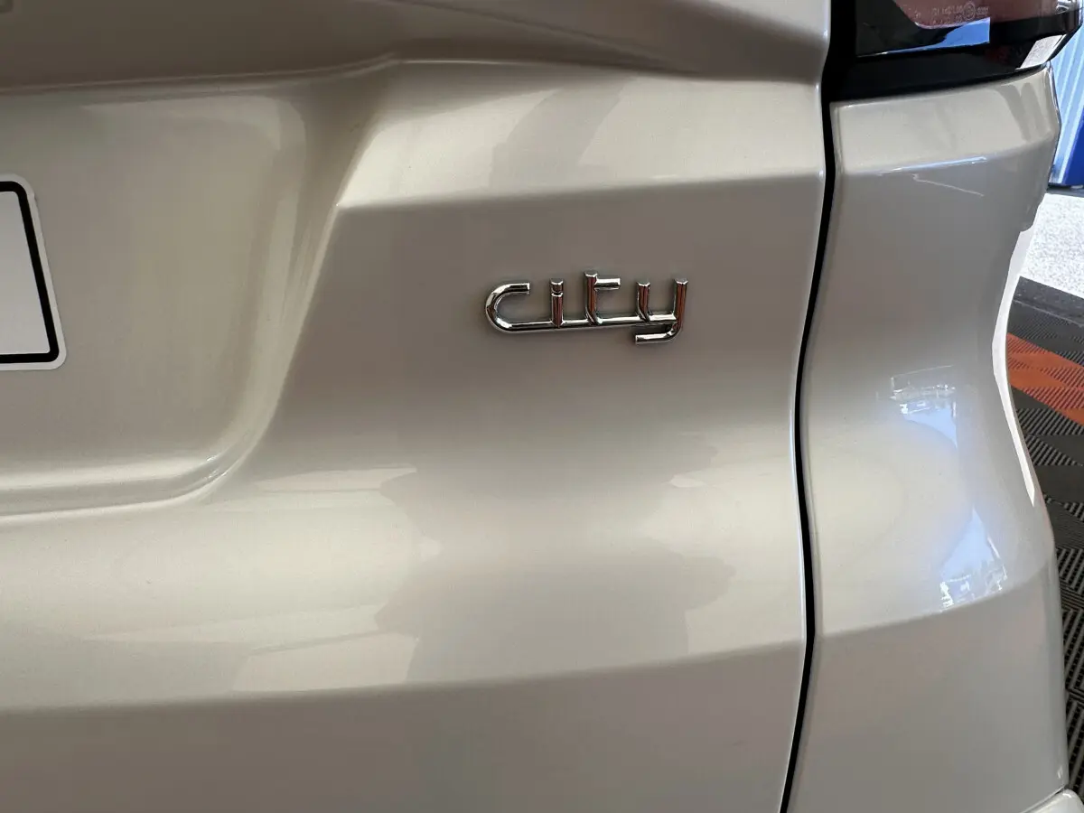 Gros plan sur l'arrière blanc d'une Aixam Ambition E City Pack 2026 avec l'inscription "city" en chrome.