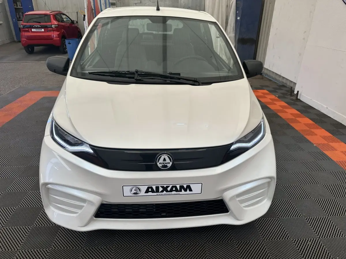 Vue de face d'une Aixam Ambition E City Pack blanche 2026 avec calandre noire et phares LED distinctifs.