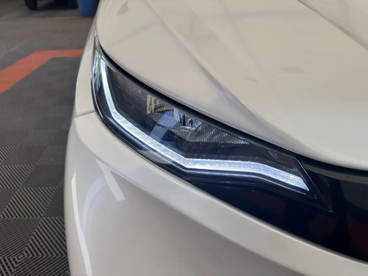 Gros plan sur le phare avant droit blanc d'une Aixam Ambition E City Pack 2026 avec éclairage LED distinctif.