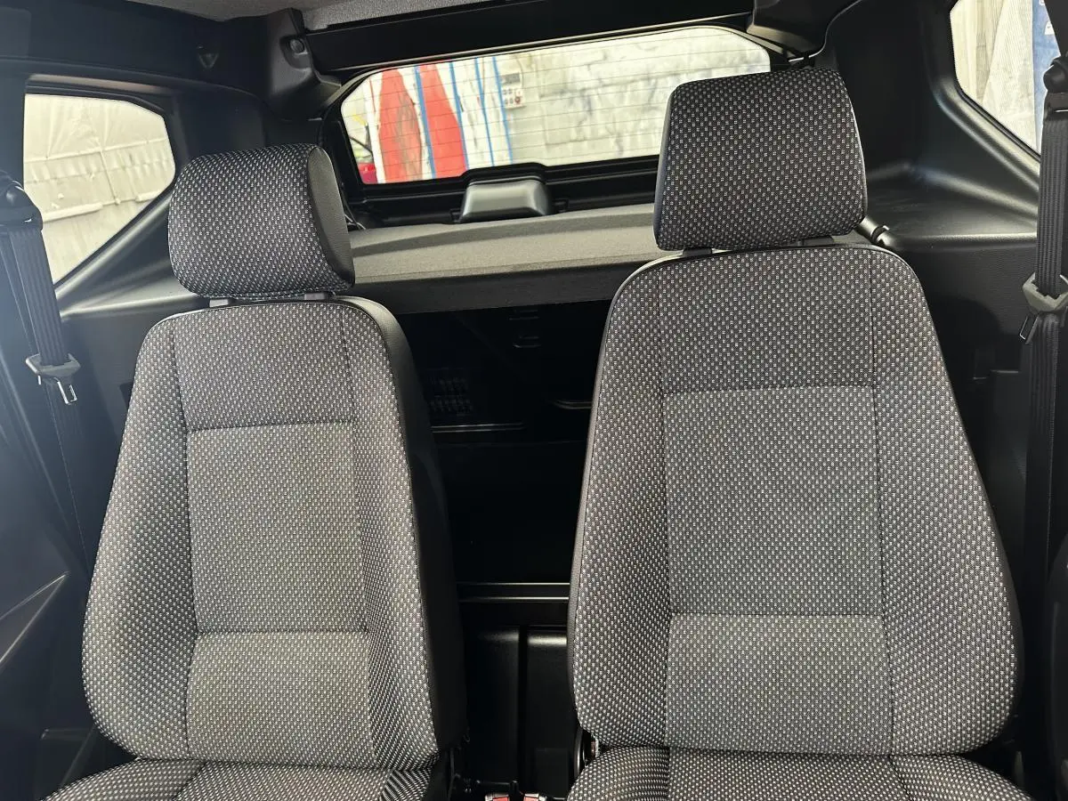 Vue intérieure centrée sur les deux sièges avant gris à motifs de l'AIXAM AMBITION E CITY PACK blanc 2026.