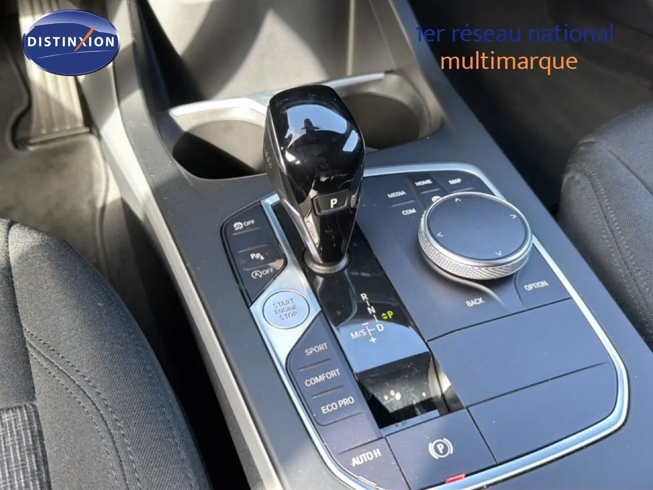 Vue rapprochée de la console centrale de la BMW Série 1 116i 2022 avec levier de vitesses noir brillant et commandes multifonctions.