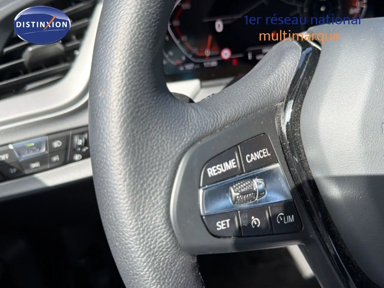 Gros plan sur le volant noir de la BMW Série 1 116i 2022, mettant en valeur les commandes de régulateur de vitesse.
