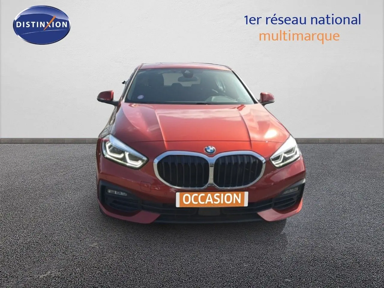Vue avant d'une BMW Série 1 116i orange Sunset Metal avec phares LED allumés sur fond neutre.