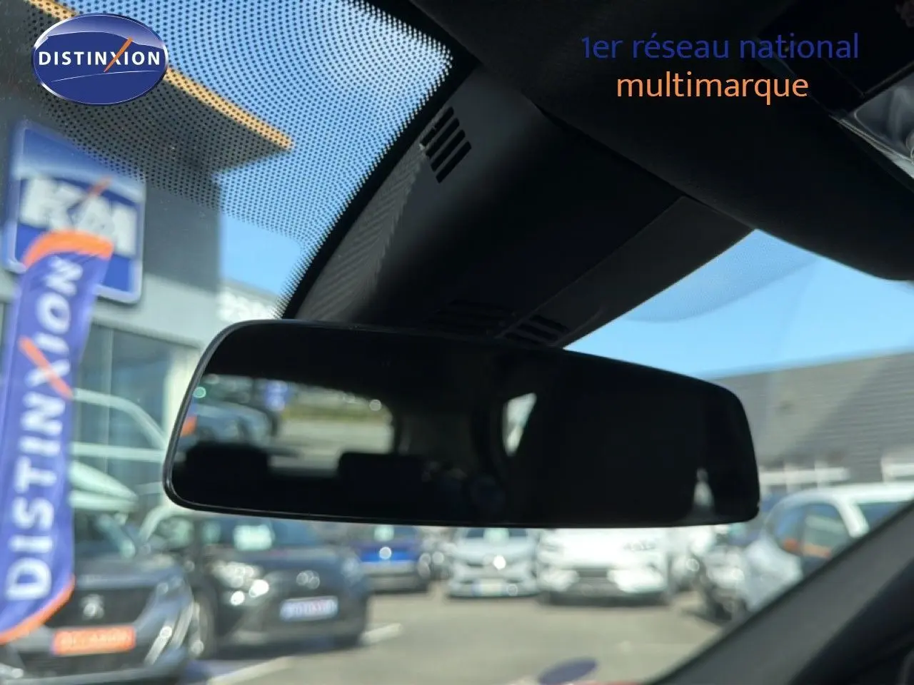 Rétroviseur intérieur de BMW Série 1 116i 2022, vue depuis l’habitacle avec reflet flou du parking extérieur.