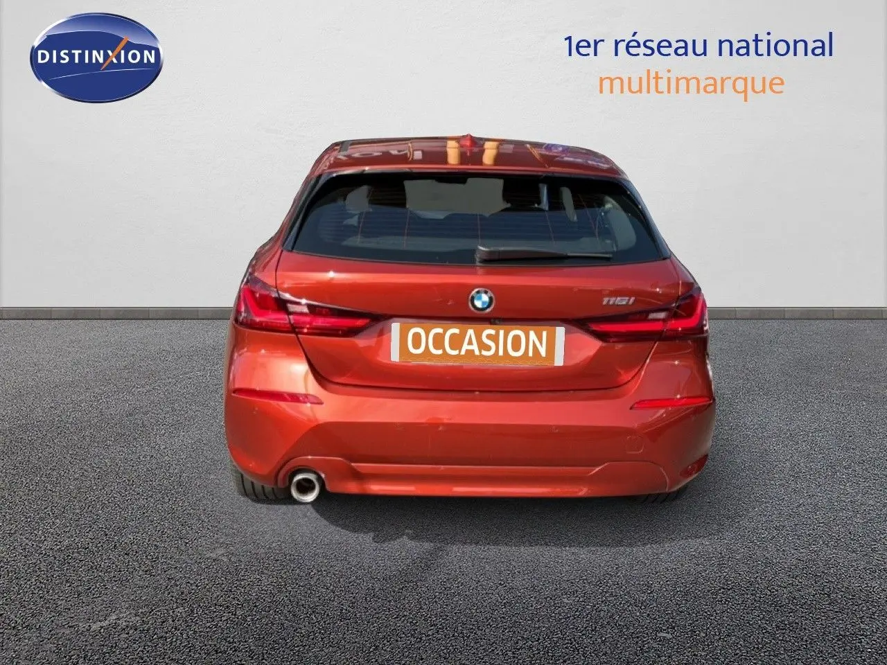 Vue arrière d'une BMW Série 1 116i orange Sunset Metal avec feu LED et sortie d'échappement visible.