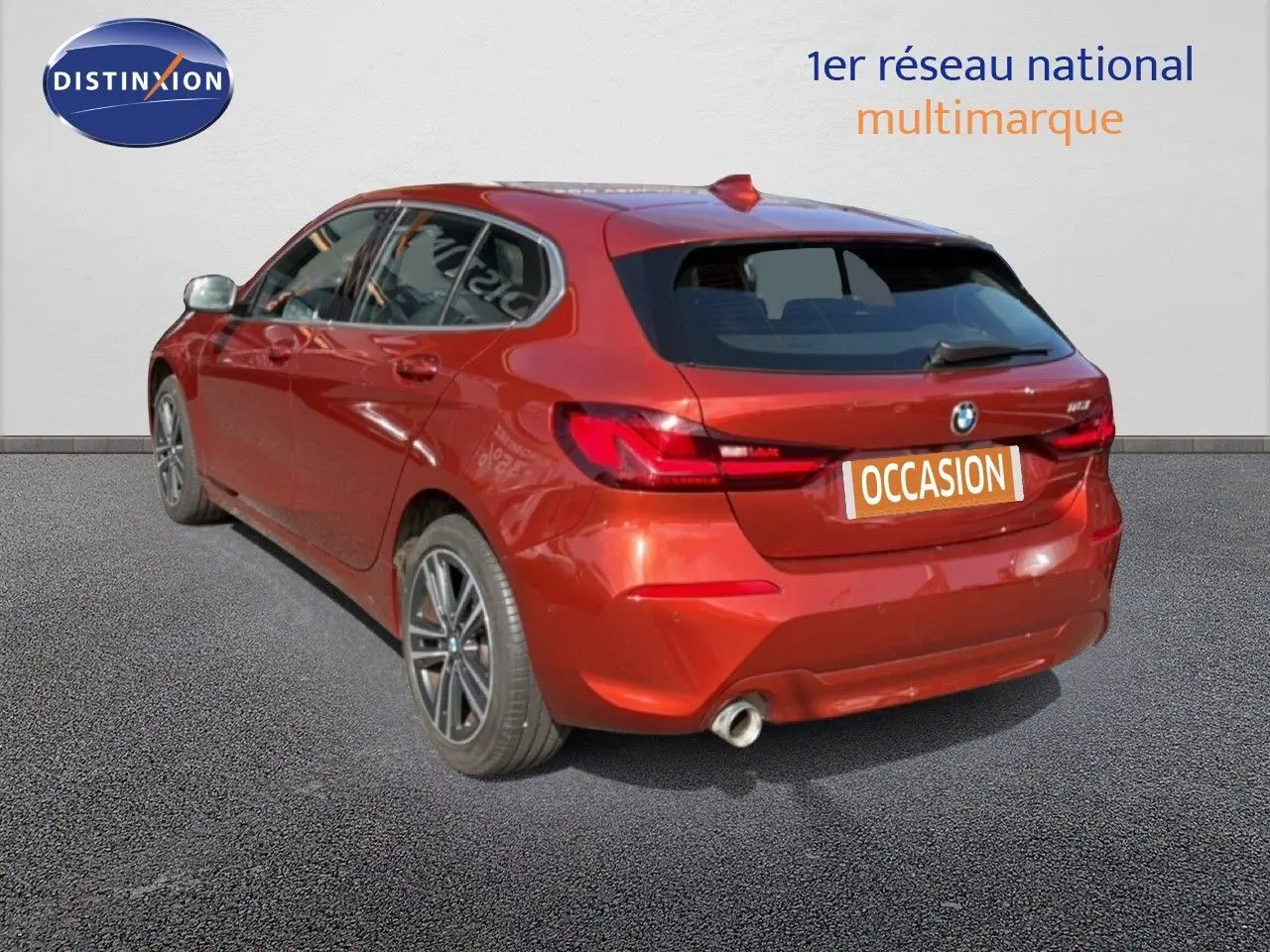 Vue 3/4 arrière droite d'une BMW Série 1 116i Business en orange Sunset métallisé avec jantes alliage et échappement simple.