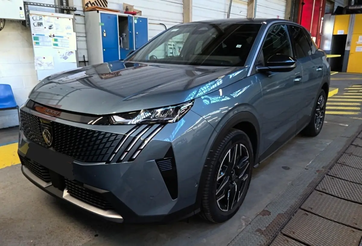 Peugeot 3008 bleu en 3/4 avant droit dans un garage, avec calandre noire et phares LED distinctifs.