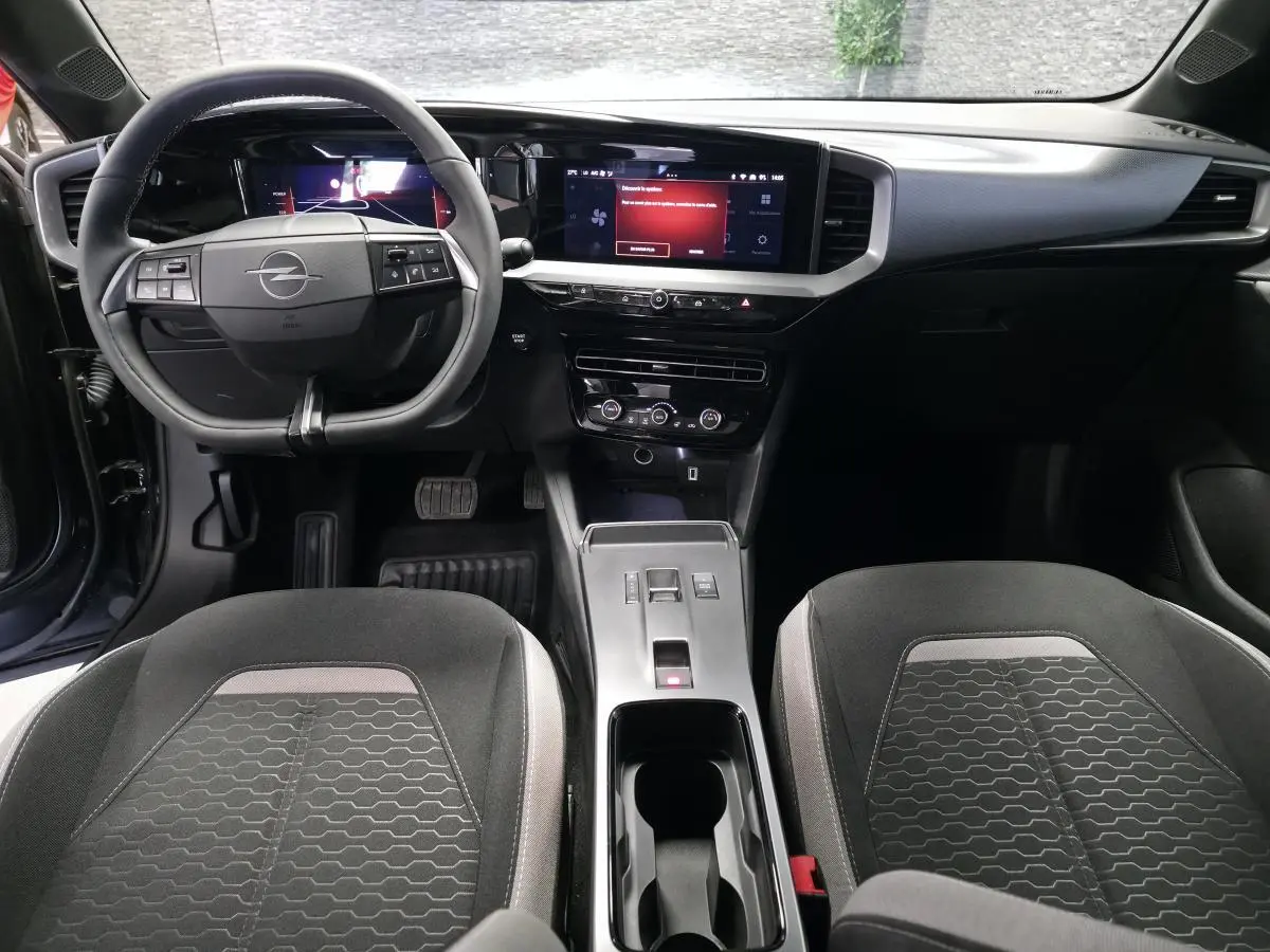 Vue intérieure avant de l'Opel Mokka 2025, tableau de bord noir avec écran tactile 10 pouces et sièges tissu gris à motifs.