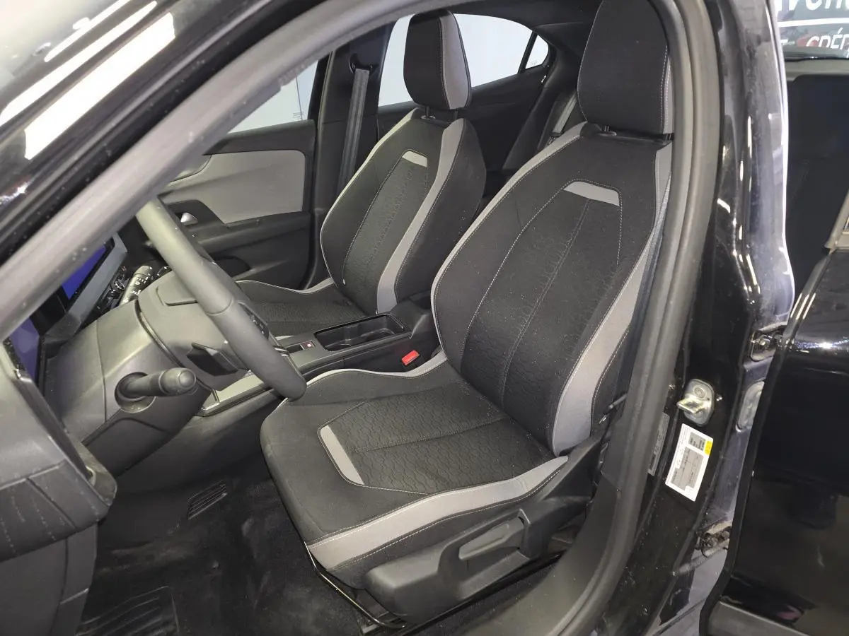 Vue intérieure côté conducteur de l’Opel Mokka noire 2025, sièges tissu gris et noir avec détails modernes.